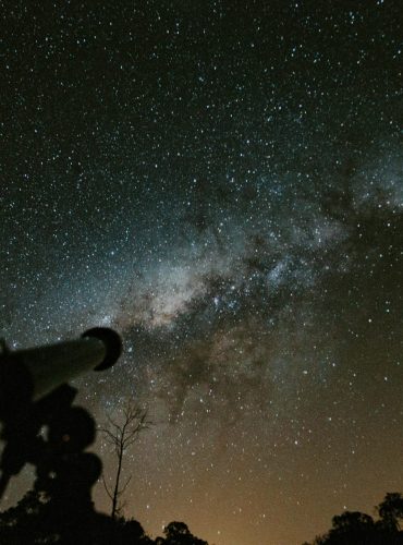 Silhouette of a telescope with a stunning Milky Way background in the night sky.